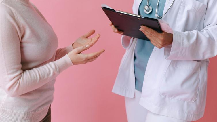 Patient and doctor with clipboard speaking from shoulder's down.